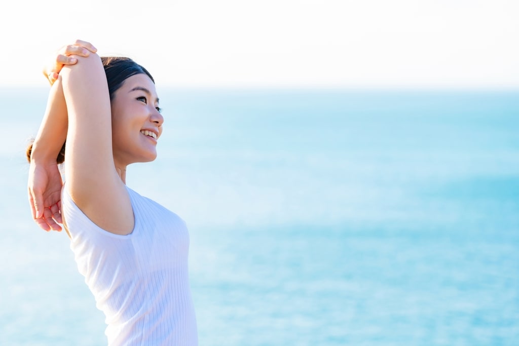 海を背景にストレッチをする健康的な女性